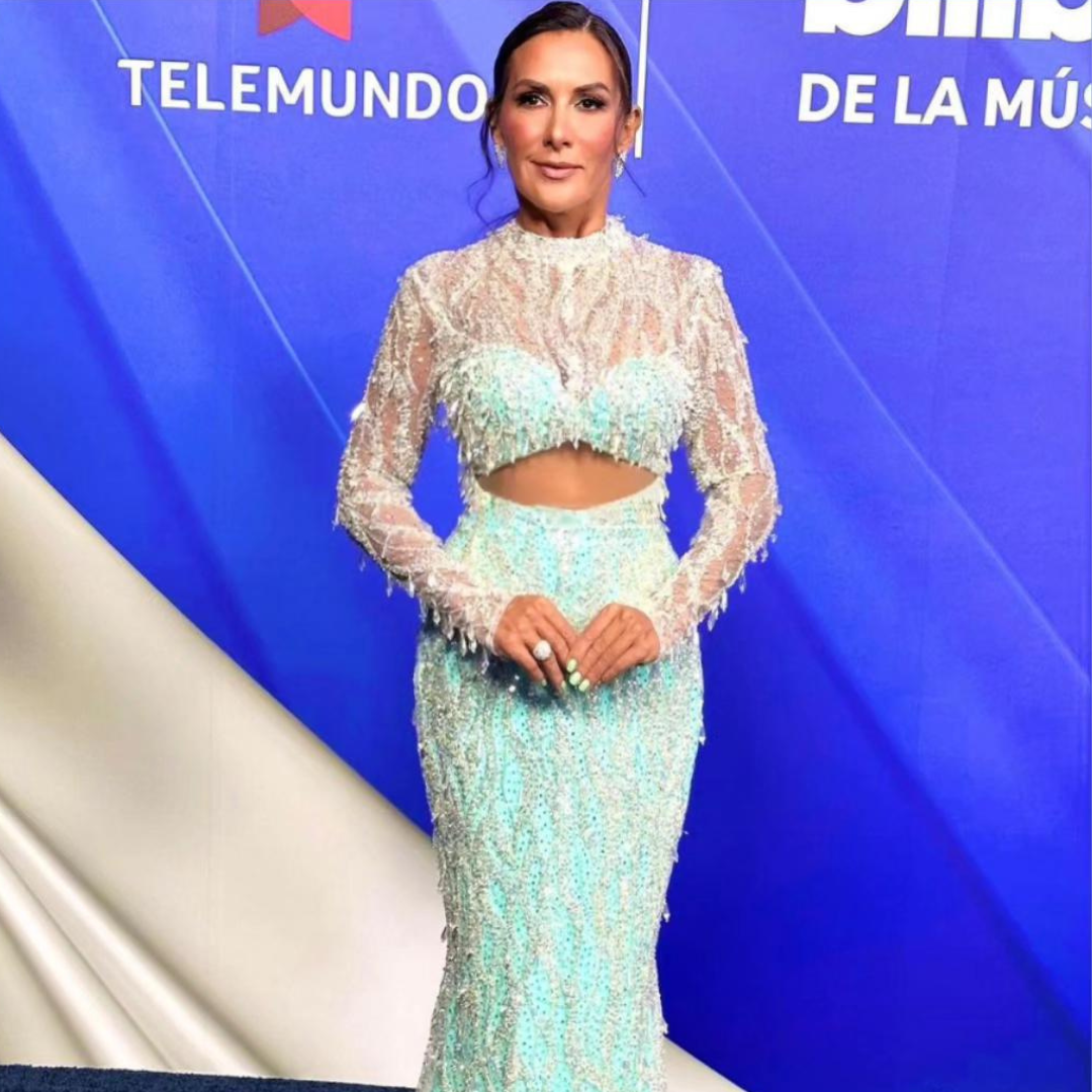Woman in a turquoise gown embroidered with silver rhinestones, showcasing sparkling rings and a sophisticated style.