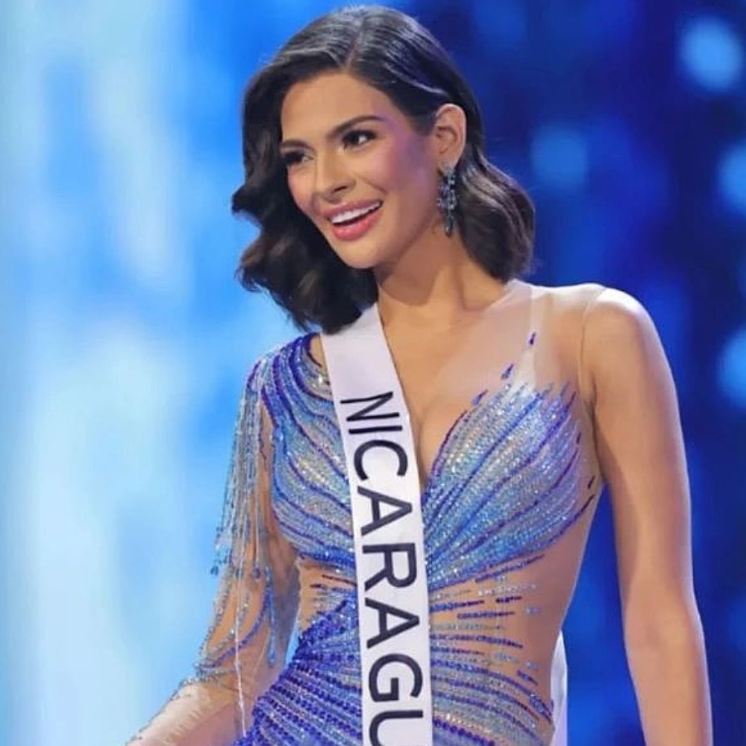 Beauty pageant contestant in a blue gradient rhinestone gown, wearing long shimmering earrings.
