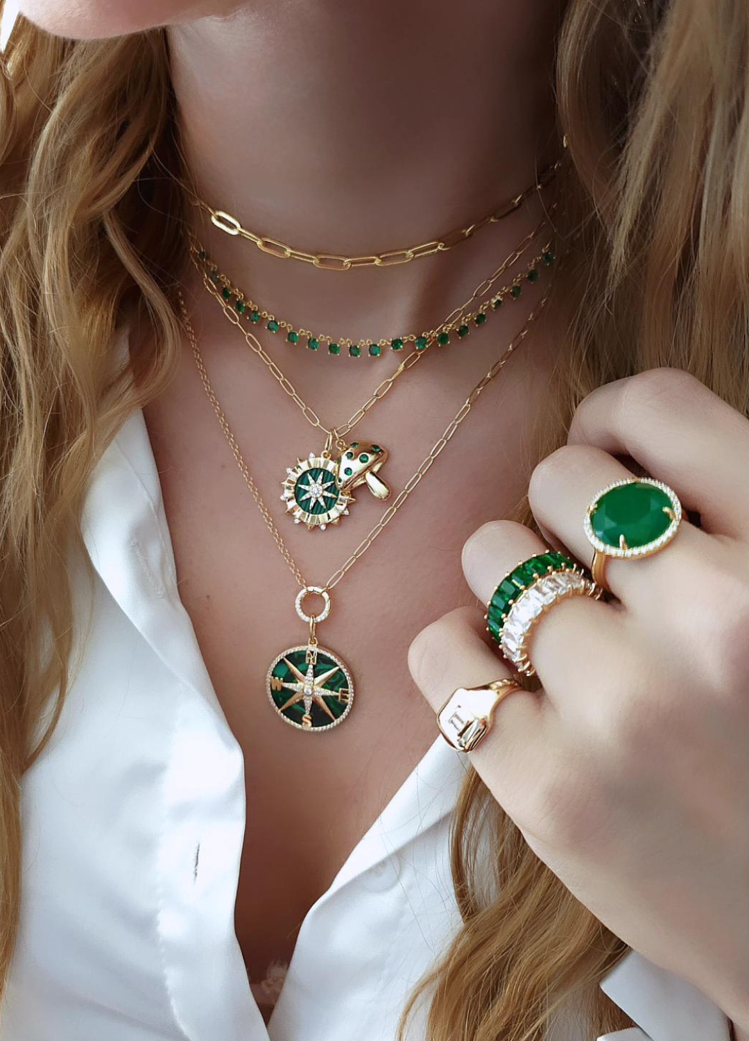 lose-up of a woman wearing layered jewelry, including necklaces, earrings, and bracelets. Her face is not visible, focusing attention on the fine details and textures of each piece. 